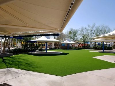 Commercial artificial turf courtyard with shade structures and paved gathering areas in Austin, Texas