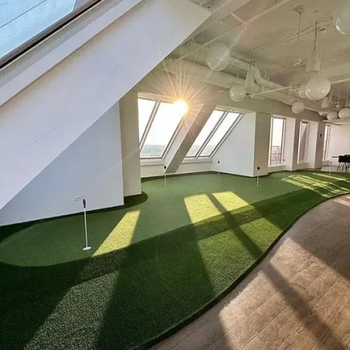 Custom indoor putting green with practice holes installed in a modern commercial interior