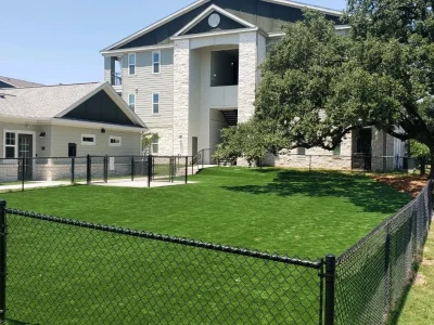 Large fenced artificial grass lawn at a commercial property in Austin, Texas