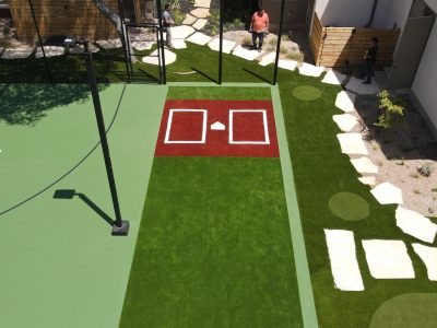 Aerial view of a multi-use sports court with basketball hoops and surrounding artificial turf in Austin, Texas