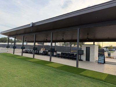 Synthetic turf tee line with covered golf hitting bays and practice mats in Austin, Texas